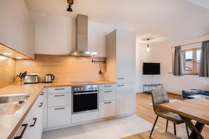 A modern kitchen with white cabinetry, a built-in oven, and a wooden countertop.