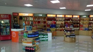 Un comercio bien iluminado con estantes repletos de diversos productos, incluyendo bebidas y alimentos envasados.