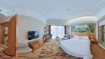 A hotel room with a bed, a TV, a desk, a chair, and a painting on the wall.