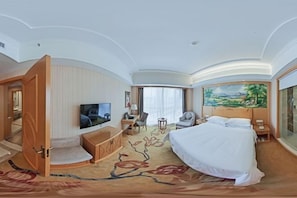 Ein Hotelzimmer mit Bett, Fernseher, Schreibtisch, Stuhl und einem Bild an der Wand.