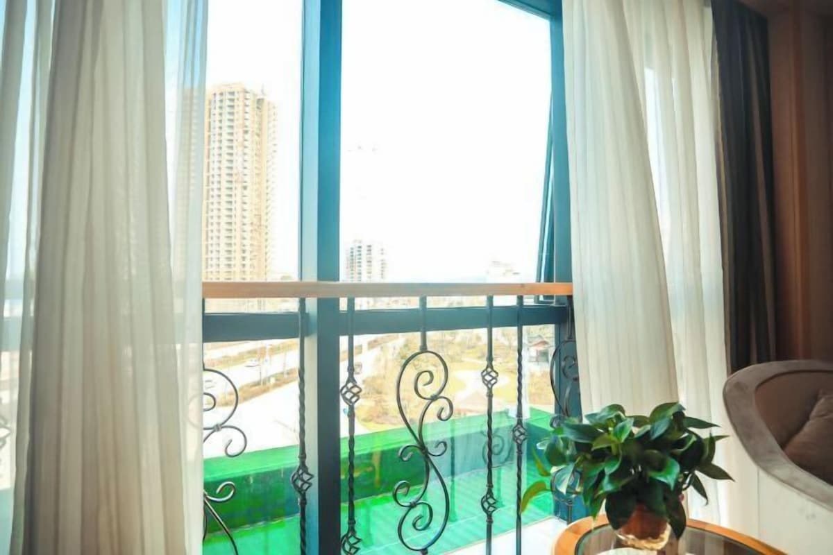 Ein Balkon mit Blick auf Gebäude, einer Topfpflanze und einem Stuhl.