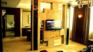 A modern living room with a flat-screen TV mounted on a marble wall, a red sofa, and a chandelier. - Donghua Hotel (Zherong)