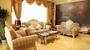 A luxurious living room with two ornate sofas, a coffee table, and a large painting on the wall. - Donghua Hotel (Zherong)
