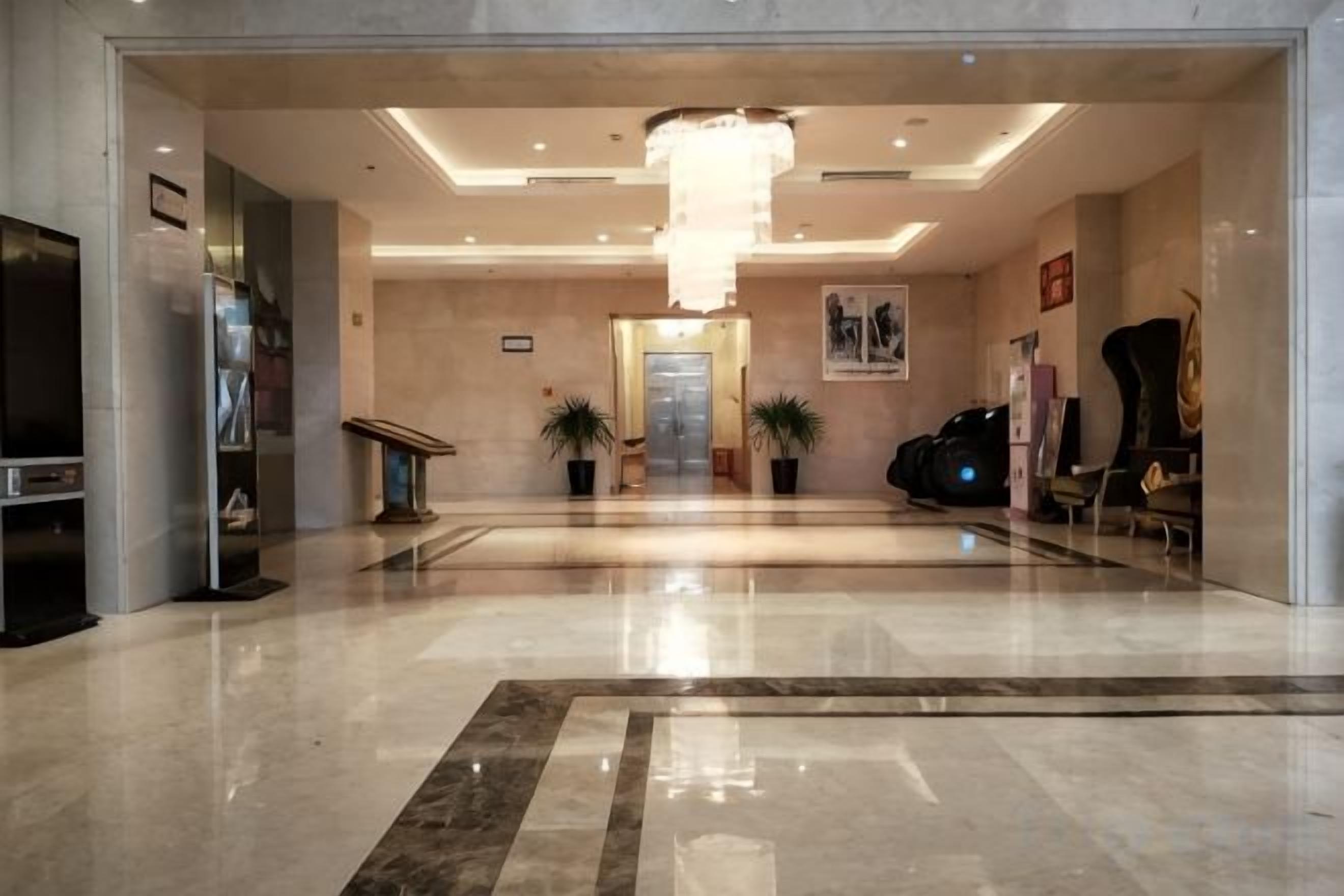 A hotel lobby with a chandelier, a reception desk, and a seating area.