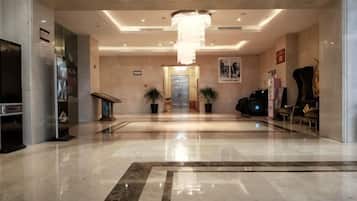A hotel lobby with a chandelier, a reception desk, and a seating area.