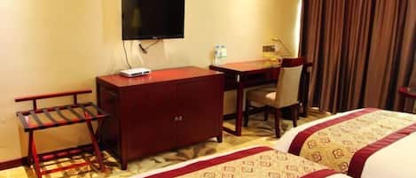 Una habitación de hotel con cama, escritorio, silla, televisor y una pequeña mesa.
