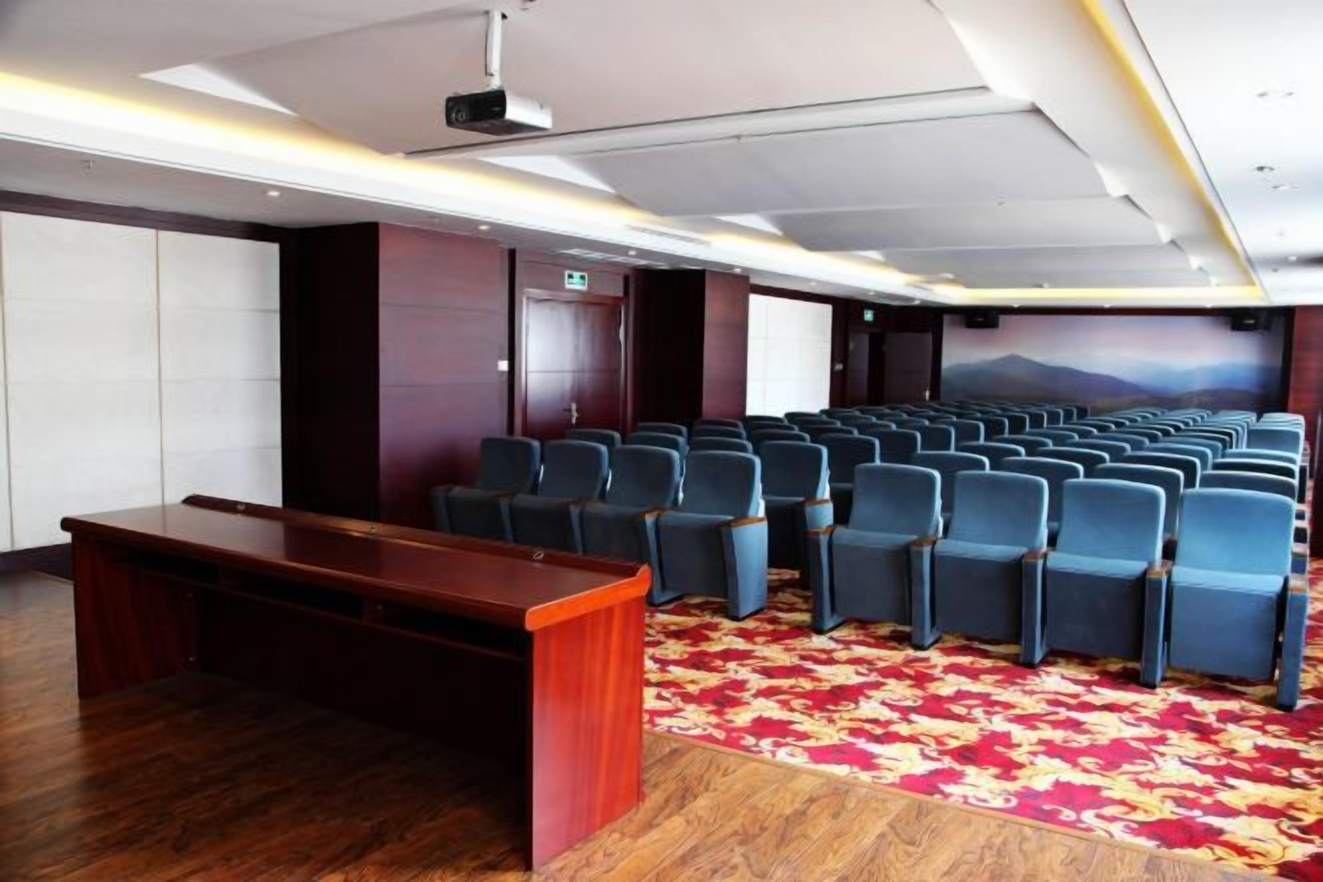 A conference room with rows of chairs, a podium, and a carpeted floor.