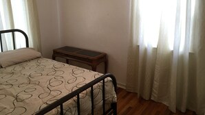 A bedroom with a bed, a small wooden table, and a window with curtains. - Classic pretty home with nice patio in Rigby. (Rigby)