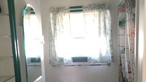 A small bathroom with a white sink, a mirror, and a window with floral curtains. - Classic pretty home with nice patio in Rigby. (Rigby)