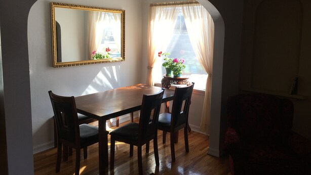 A dining area with a wooden table and chairs, a mirror on the wall, and a window with curtains. - Classic pretty home with nice patio in Rigby. (Rigby)