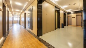 Un largo pasillo bien iluminado con ascensores y puertas a ambos lados.