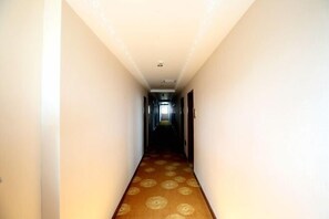 A narrow hallway with patterned carpet and white walls. - Xingfujiudian (Chongqing)