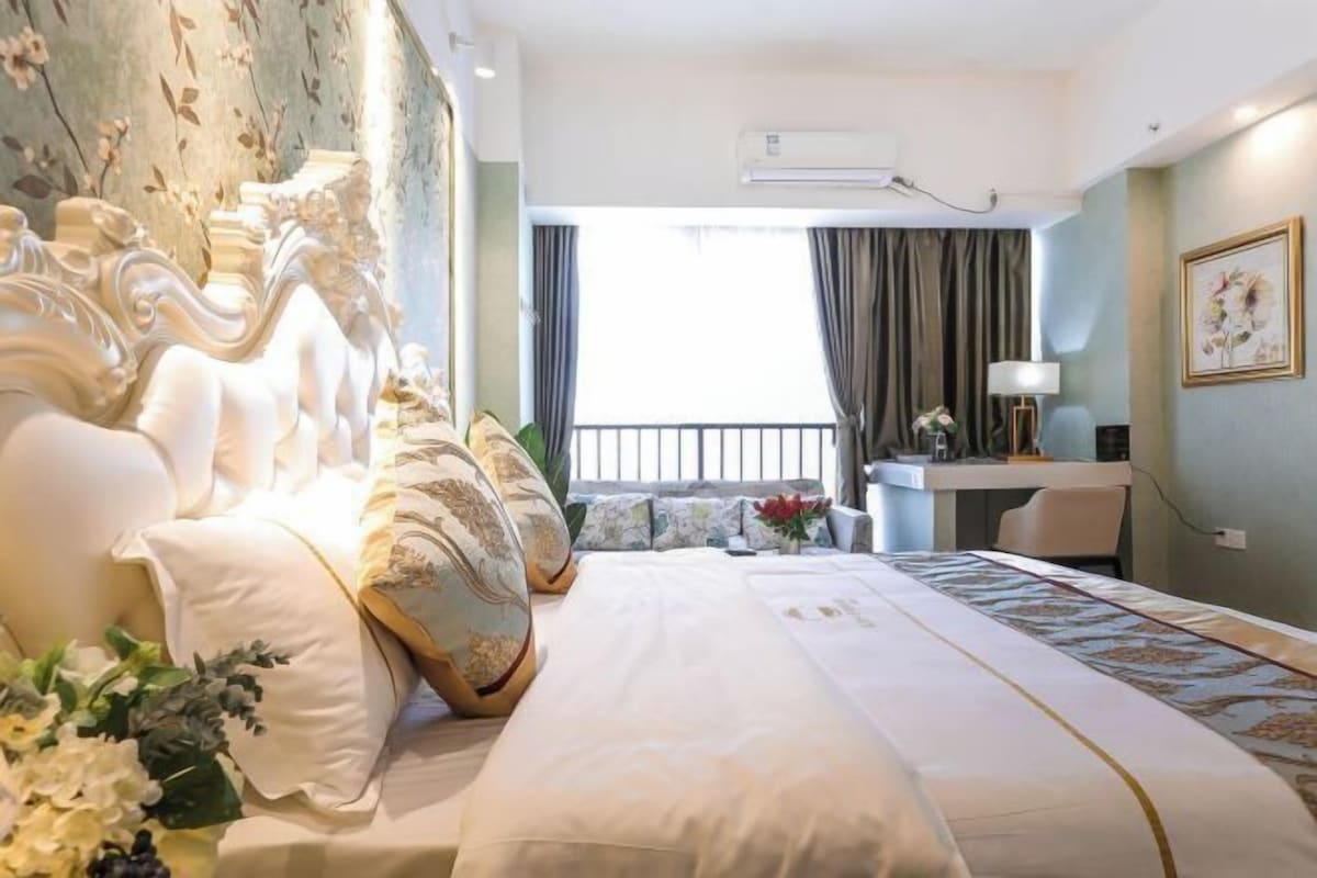 A hotel room with a large bed, a desk, and a view of the outside.