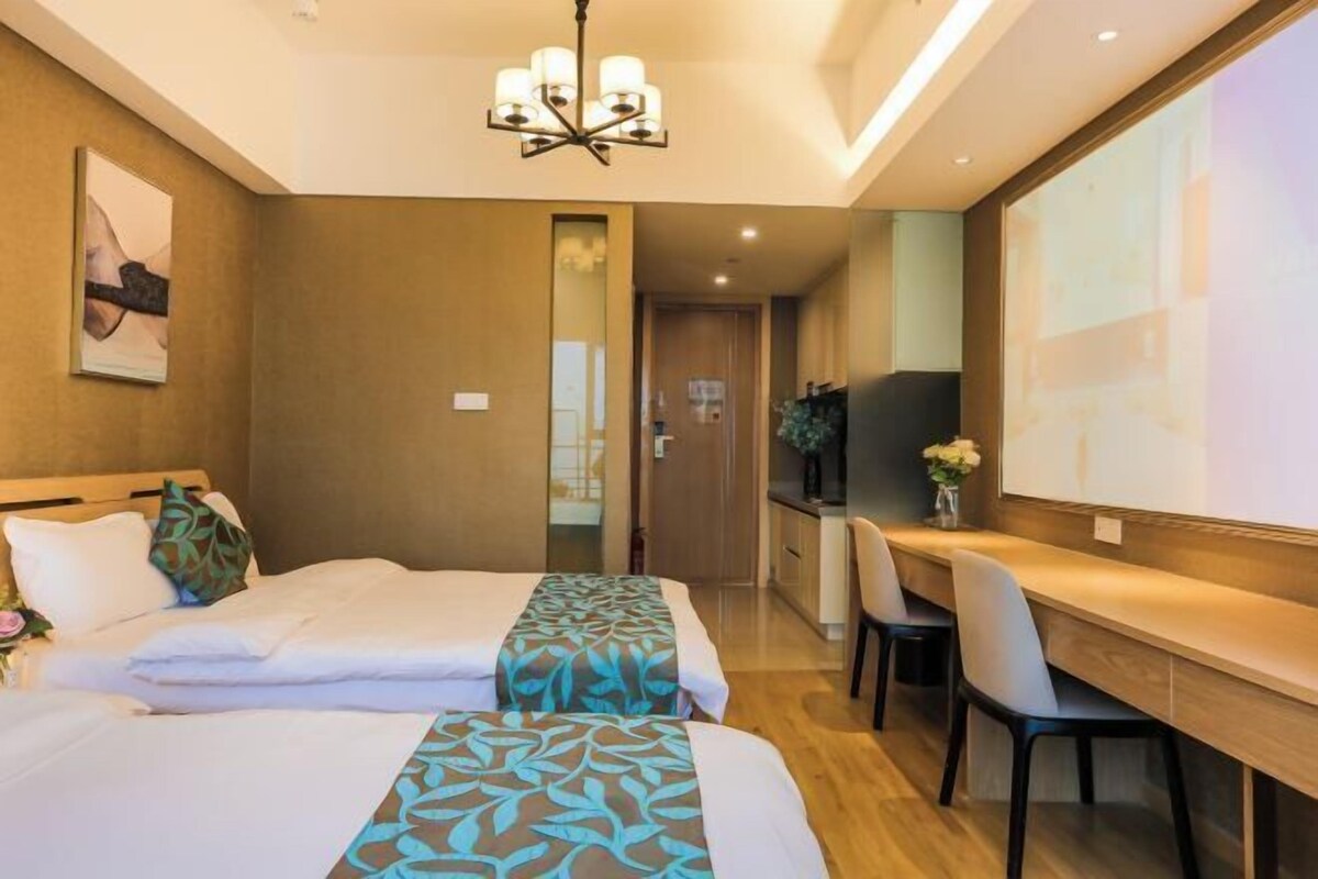 A hotel room with two beds, a desk, and a television.