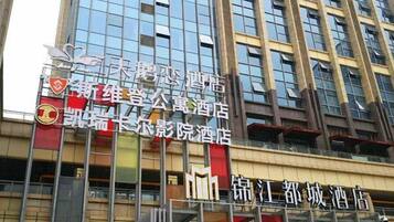 A multi-story building with several hotel signs, including '新维泰公寓酒店' and '锦江都城酒店'.