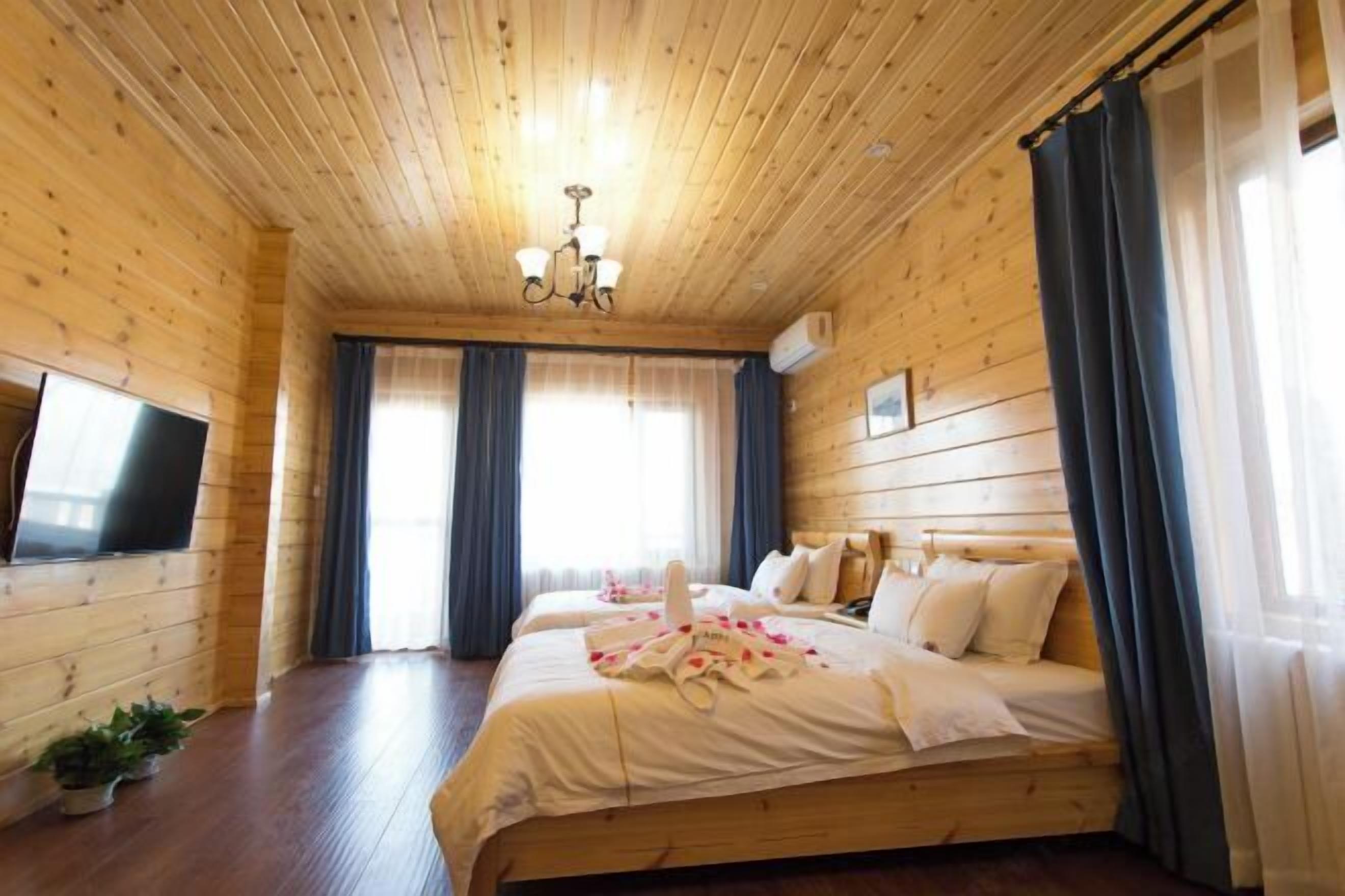 A wooden-paneled room with a large bed, a flat-screen TV, and a chandelier.