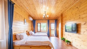 Una habitación de cabaña de madera con dos camas, un televisor y una ventana con cortinas.