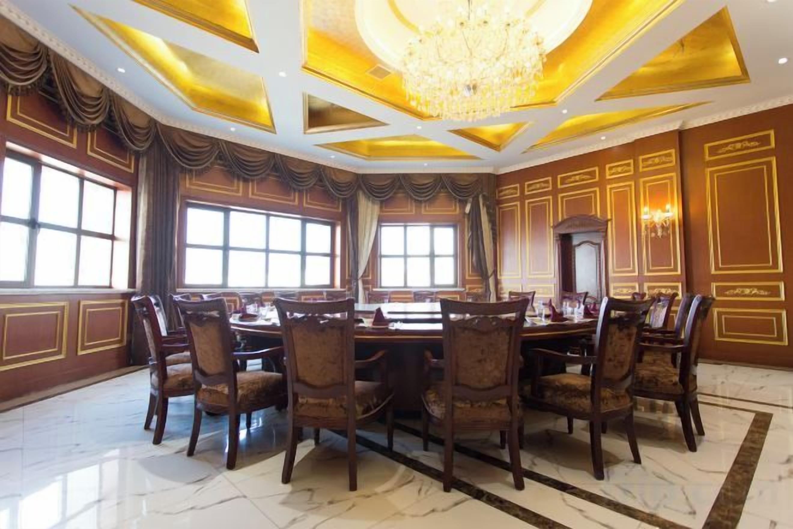 A formal dining room with a large table and chairs, a chandelier, and large windows.