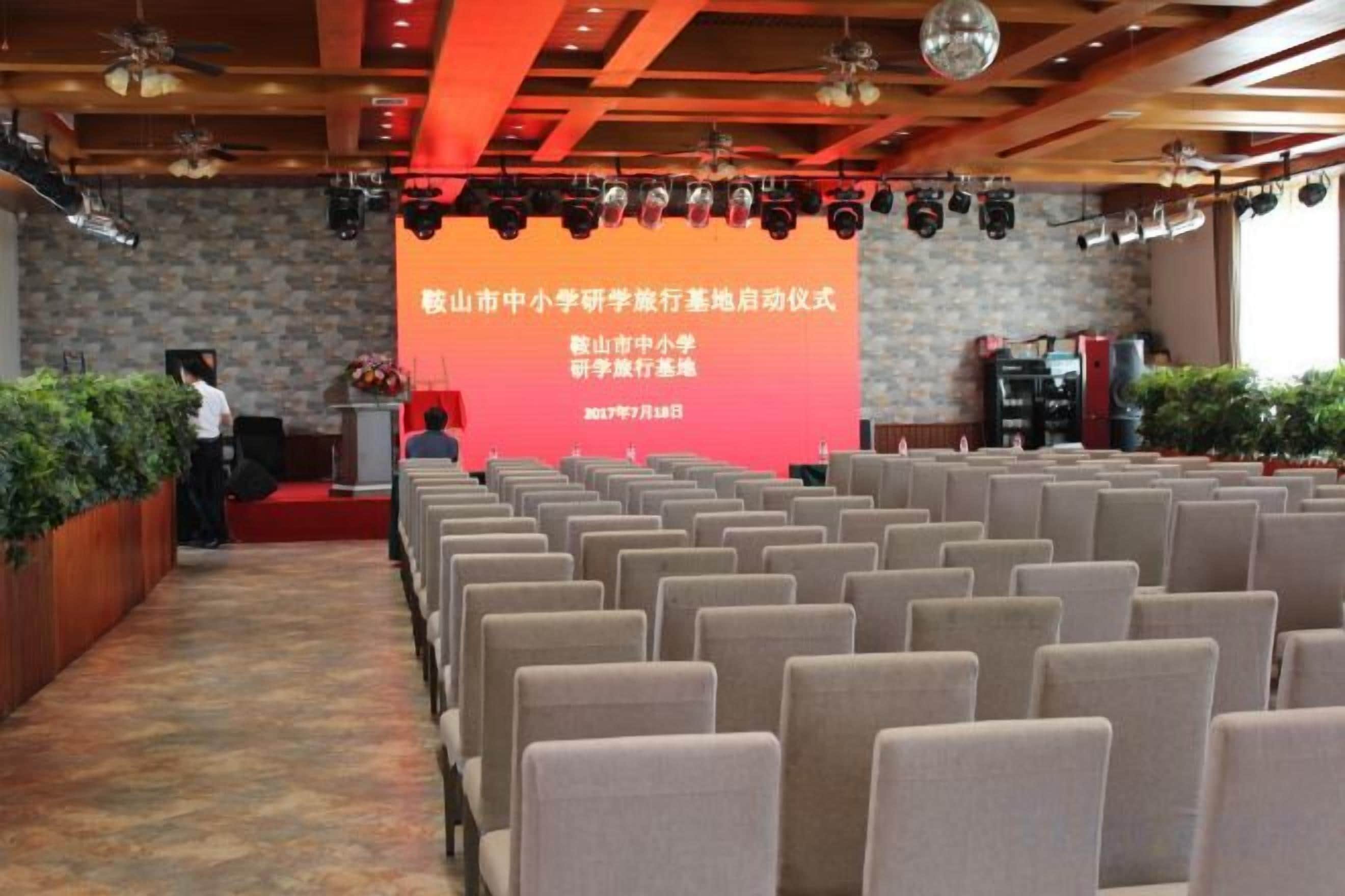 A conference room with rows of chairs facing a stage with a podium and a large screen displaying text.