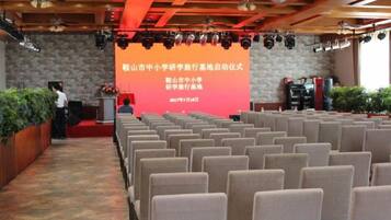 A conference room with rows of chairs facing a stage with a podium and a large screen displaying text.