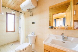 A bathroom with a toilet, shower, sink, and wooden ceiling.