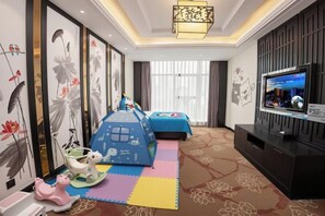 A hotel room with a TV, a bed, a play area, and artwork on the walls. - CHUXI GRAND HOTEL (Tongren)