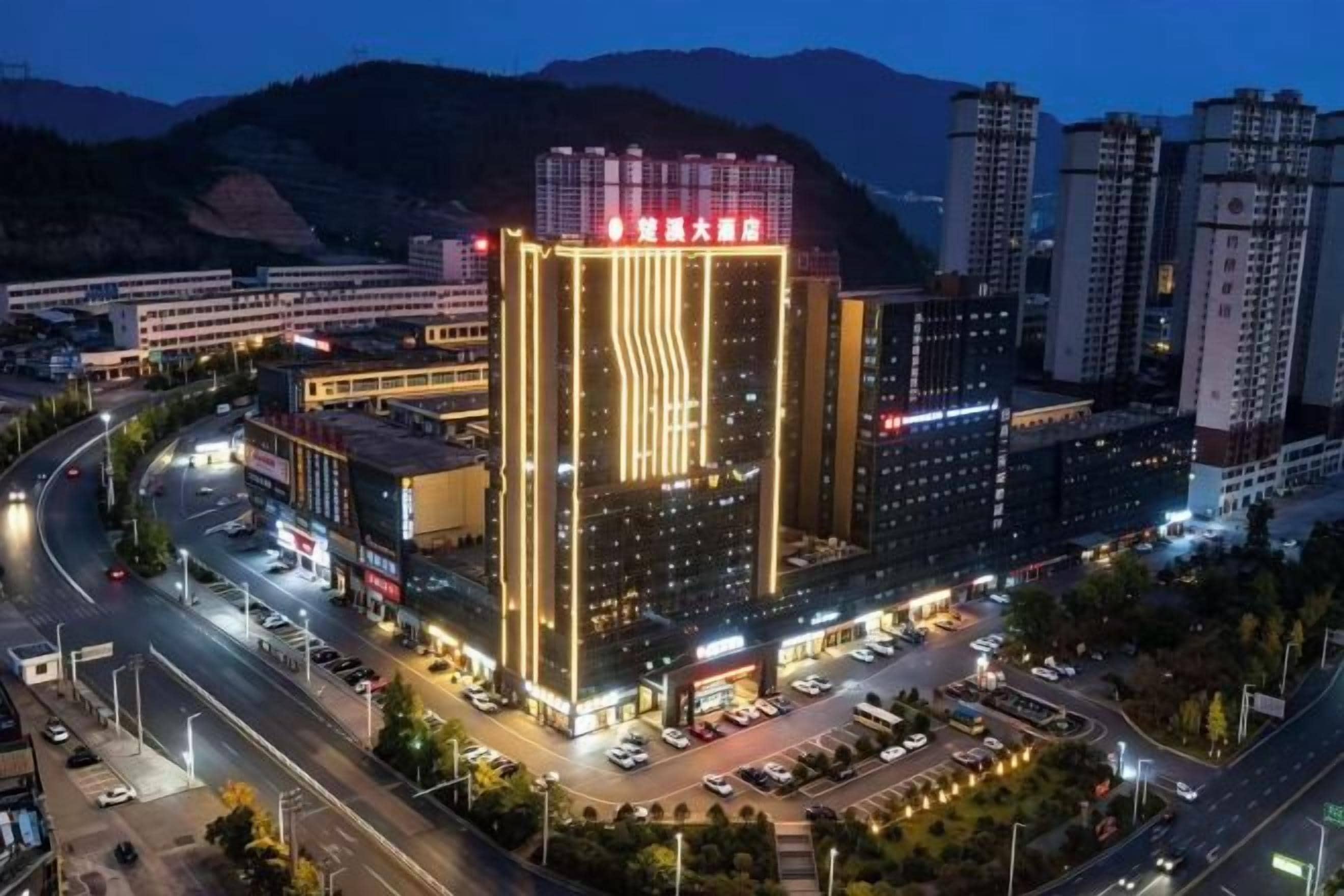 Hotel de diversos pisos amb un destacat disseny d'il·luminació vertical, envoltat d'una zona de pàrquing i carreteres.