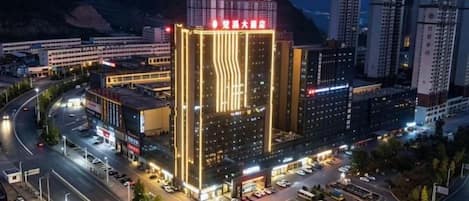 A multi-story hotel with a prominent vertical light strip design, surrounded by a parking area and roads.