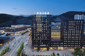 A modern hotel with a prominent entrance, multiple floors, and a parking lot. - CHUXI GRAND HOTEL (Tongren)