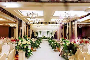 A banquet hall with rows of white chairs, floral centerpieces, and chandeliers. - CHUXI GRAND HOTEL (Tongren)