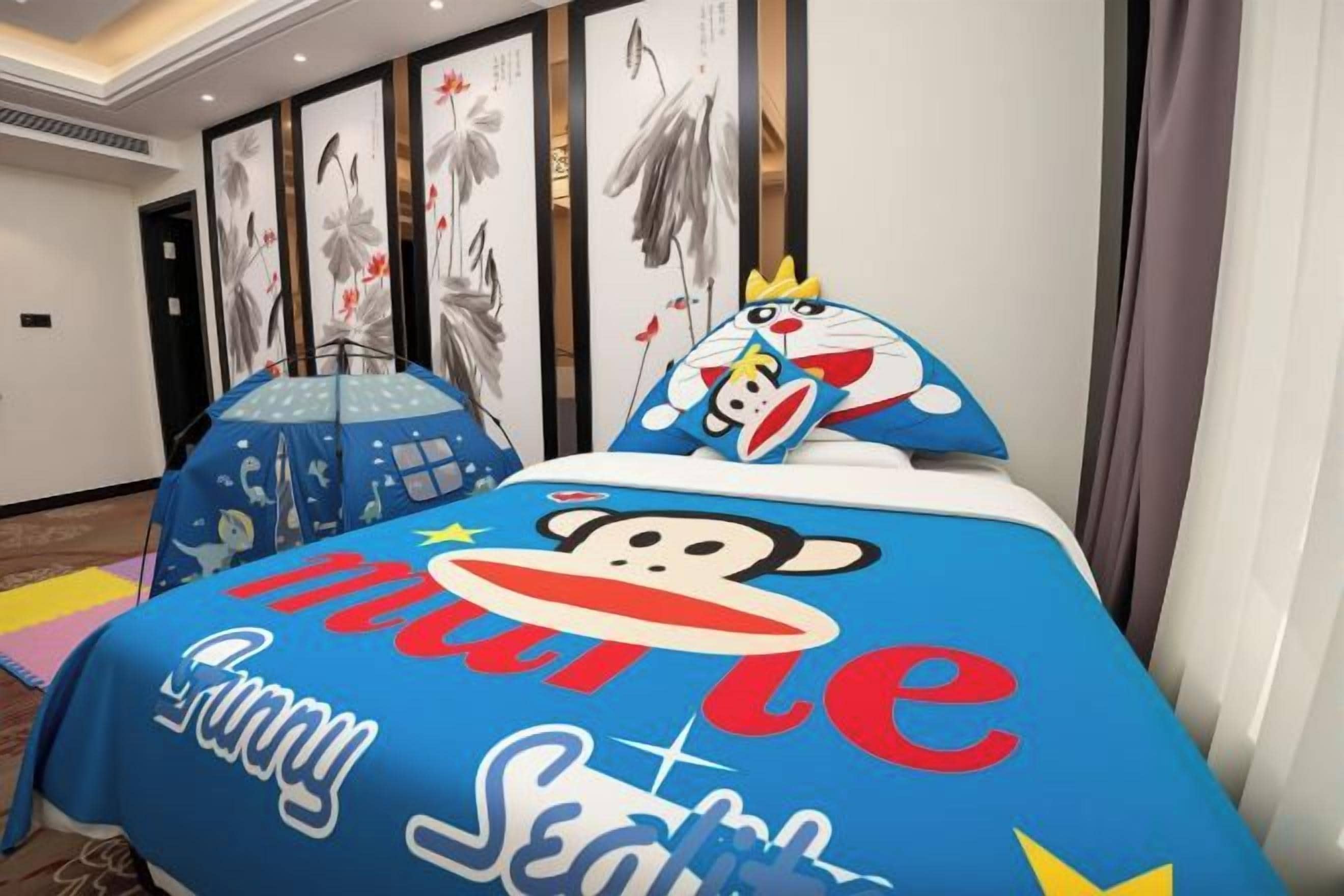 A hotel room with a bed featuring a colorful bedspread with cartoon characters and the words 'Sunny Seattle.'