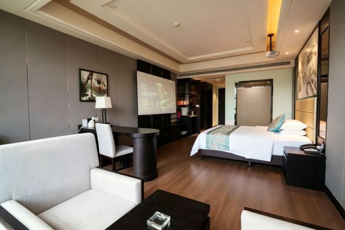 Ein Hotelzimmer mit Bett, Sofa, Schreibtisch und Fernseher.