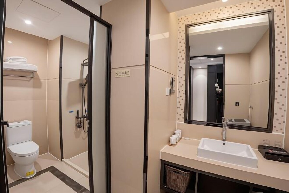 A modern bathroom with a toilet, shower, and sink.