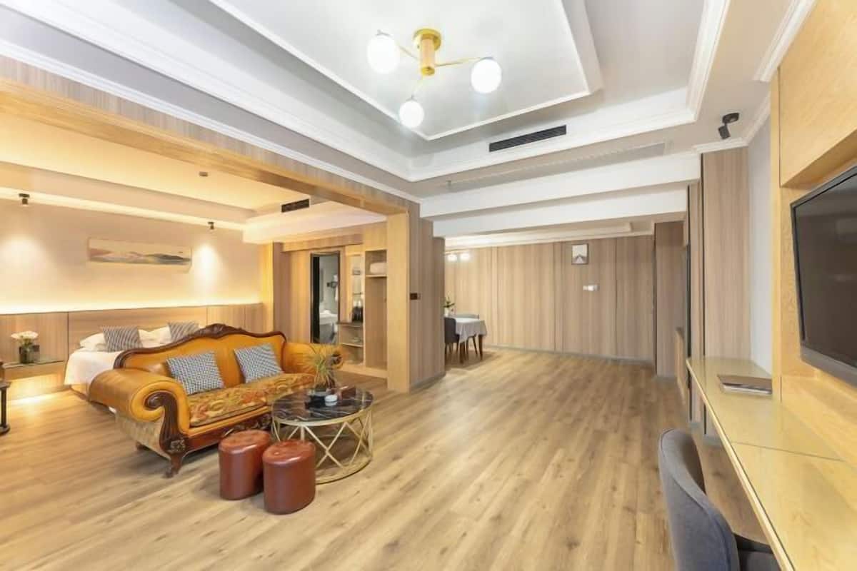 Uma sala de estar ampla com piso de madeira, um sofá, uma mesa de centro e uma televisão.