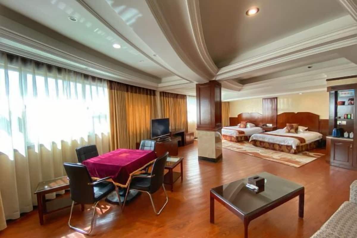 Quarto de hotel com área de refeições, televisão, cama e minibar.