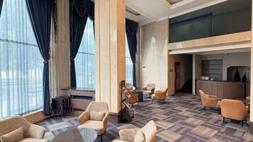 A hotel lobby with a check-in desk, seating area, and large windows.