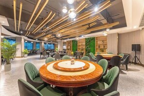 A modern conference room with a round table, green chairs, and a green wall with plants. - Oukai'er Hotel (Tonglu)