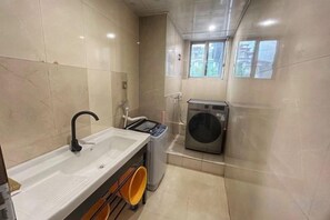 A compact bathroom with a sink, a washing machine, and a window. - Oukai'er Hotel (Tonglu)