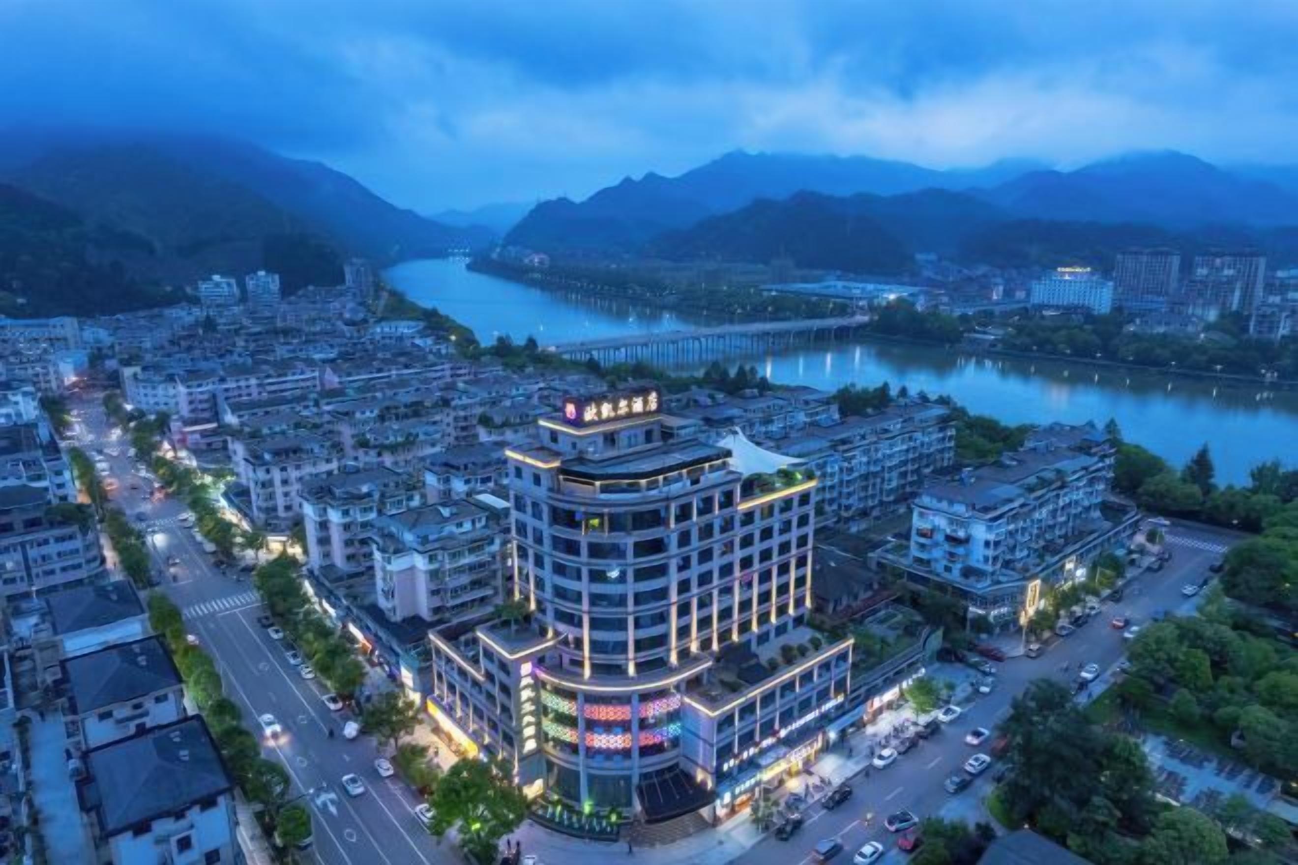 A multi-story hotel with a central atrium, surrounded by a cityscape and a river.