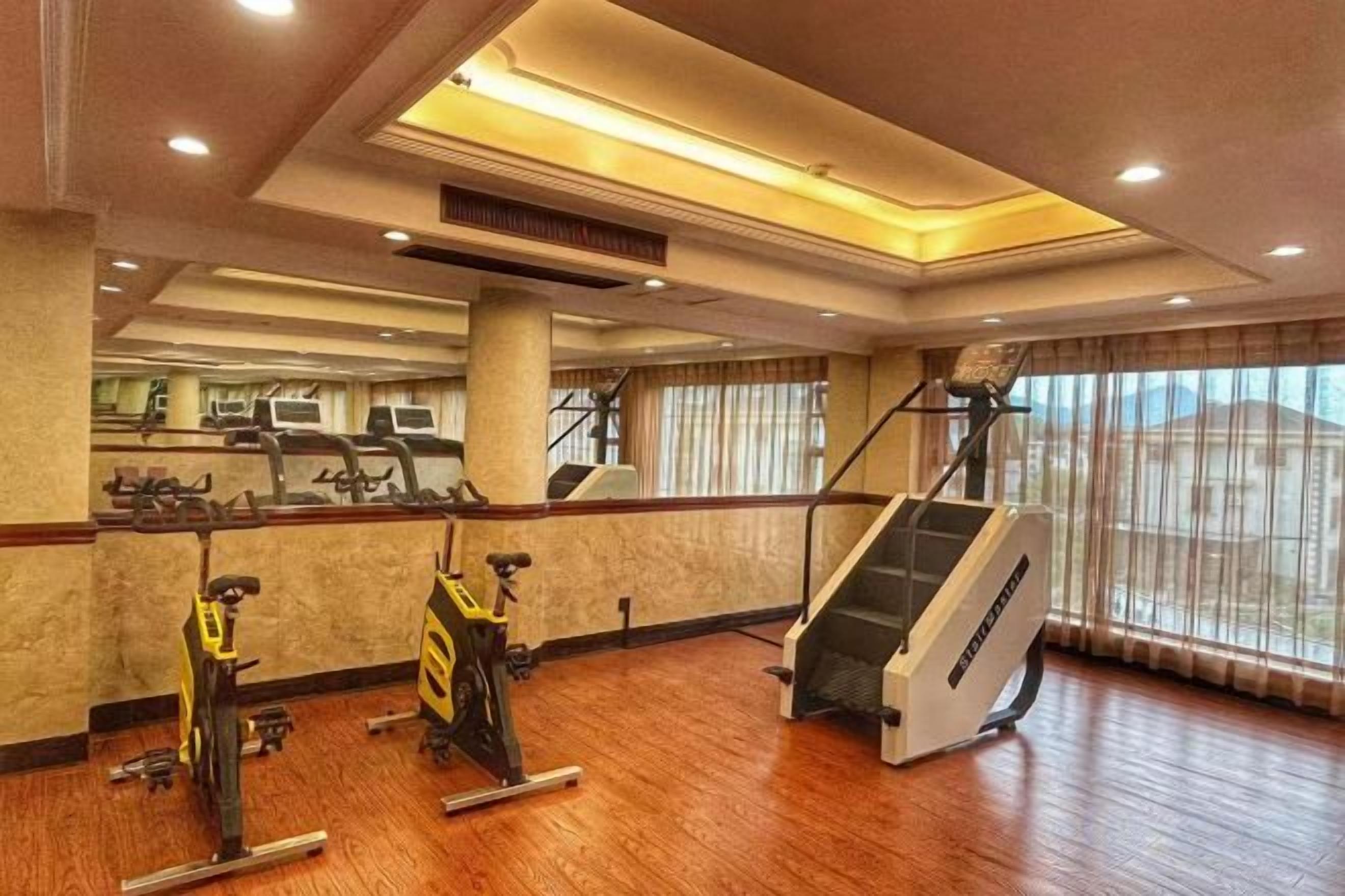 A gym with exercise equipment, a staircase, and large windows.