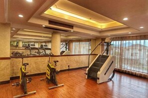 A gym with exercise equipment, a staircase, and large windows. - Oukai'er Hotel (Tonglu)