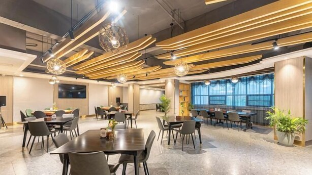 A modern conference room with multiple tables and chairs, a large window with a view, and a unique ceiling design with wooden slats and hanging lights. - Oukai'er Hotel (Tonglu)
