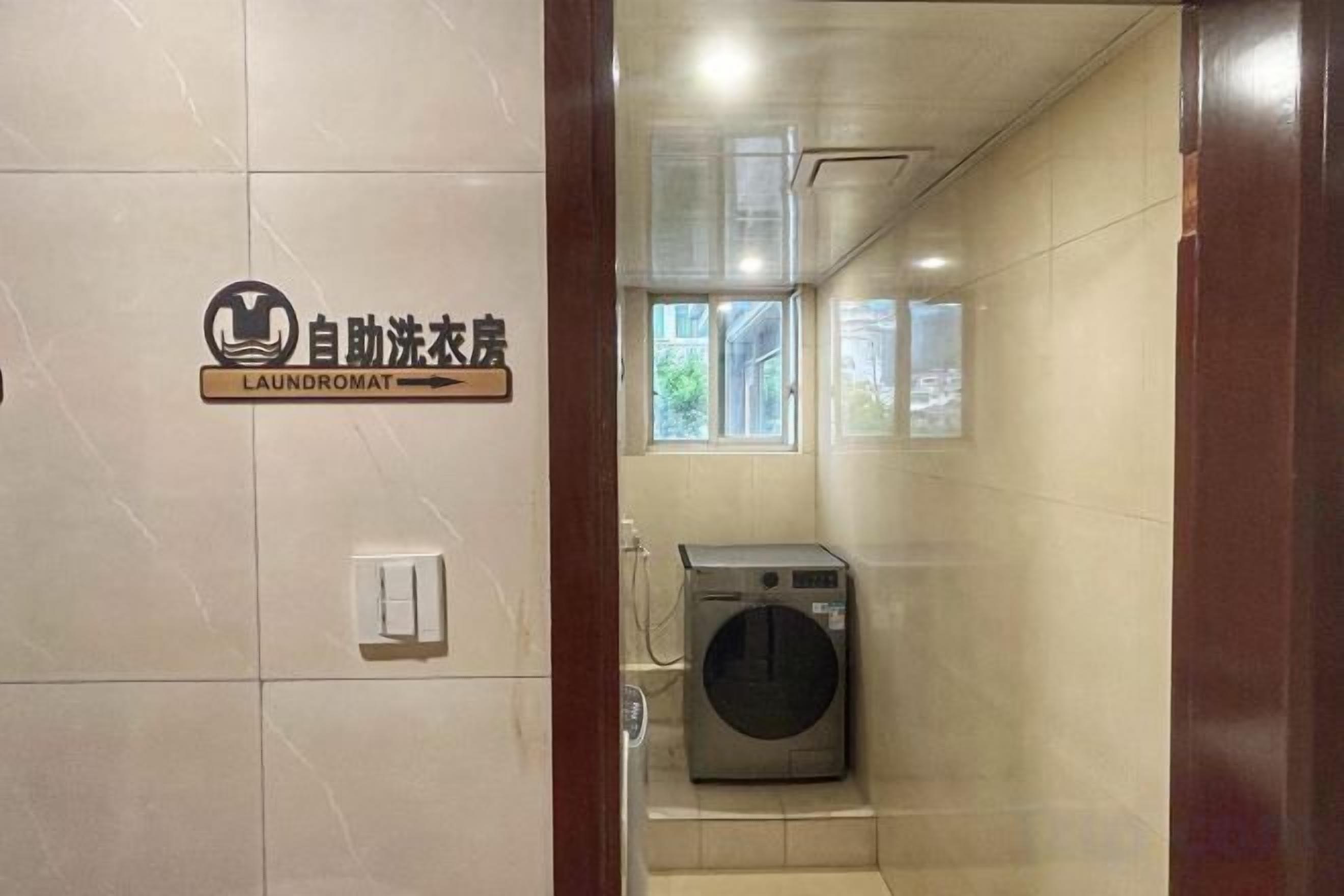 A laundromat with a sign, a washing machine, and a window.