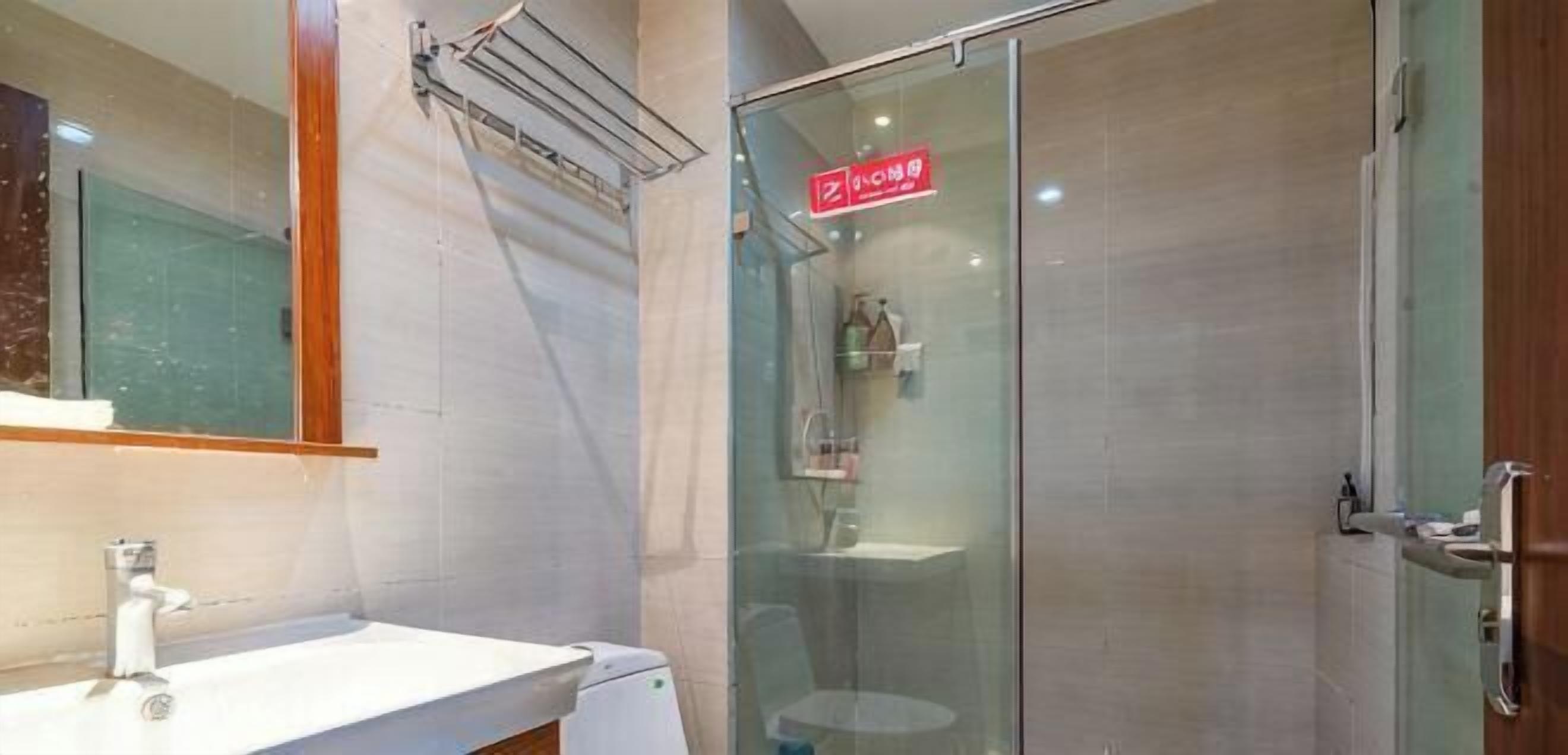 Een moderne badkamer met een douchecabine van glas, een witte wastafel en een spiegel.