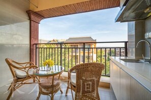 Un balcon agrémenté de meubles en osier, d’une table ronde et offrant une vue sur les immeubles.