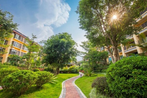 A pathway leading through a well-maintained garden area with buildings on either side.