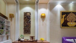 Een receptiegedeelte met een receptiebalie, een decoratief paneel aan de muur en een wandlamp.