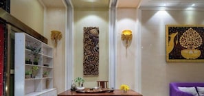 Een receptiegedeelte met een receptiebalie, een decoratief paneel aan de muur en een wandlamp.