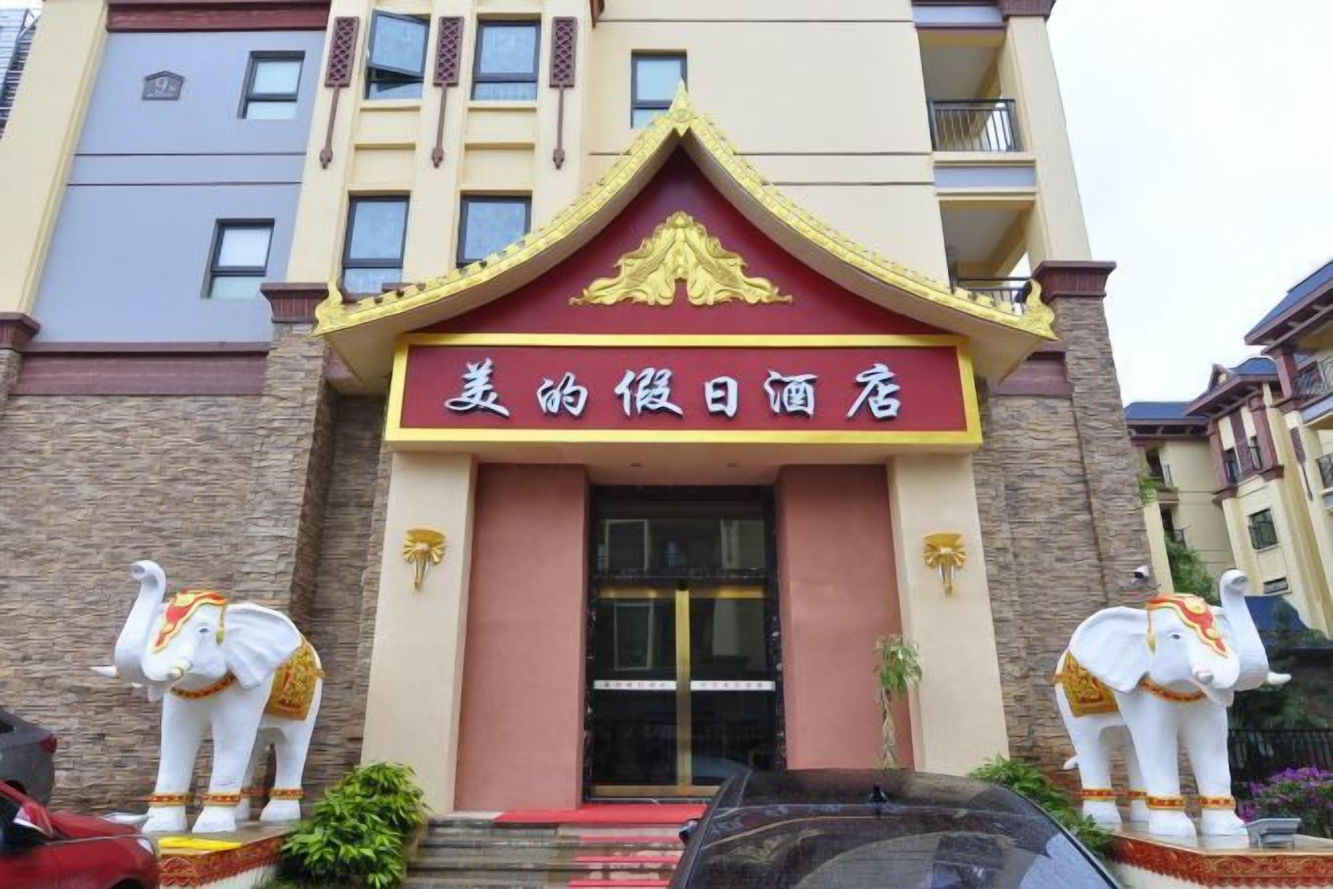 A hotel entrance with a red and gold sign, two elephant statues, and a red carpet leading to the door.