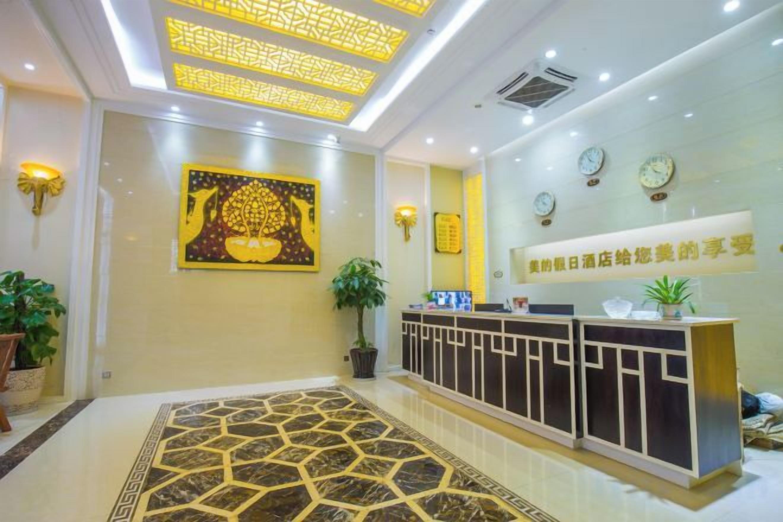 A hotel reception area with a reception desk, a patterned carpet, wall-mounted clocks, and a large framed artwork.